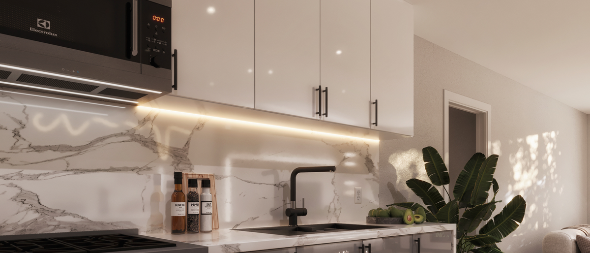 Modern kitchen interior with glossy white cabinets, a white marble backsplash, a black faucet, a black range hood, and a potted green plant on the counter.